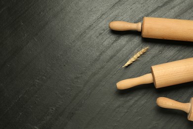 Photo of Wooden rolling pins and spike on dark gray textured table, flat lay. Space for text