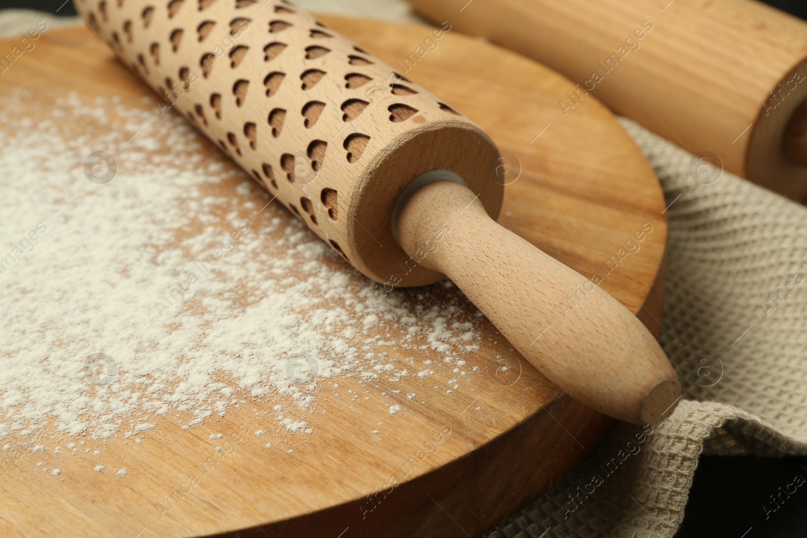 Photo of Wooden rolling pin, board and flour on table, closeup