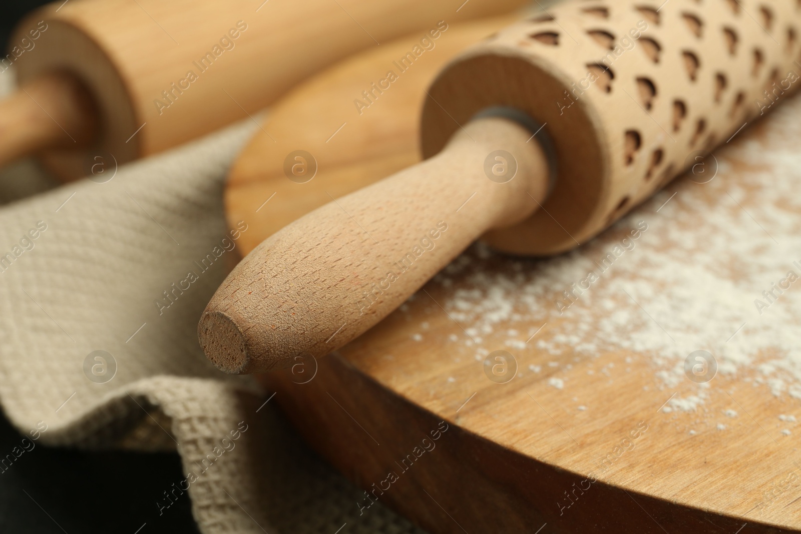 Photo of Wooden rolling pin, board and flour on table, closeup