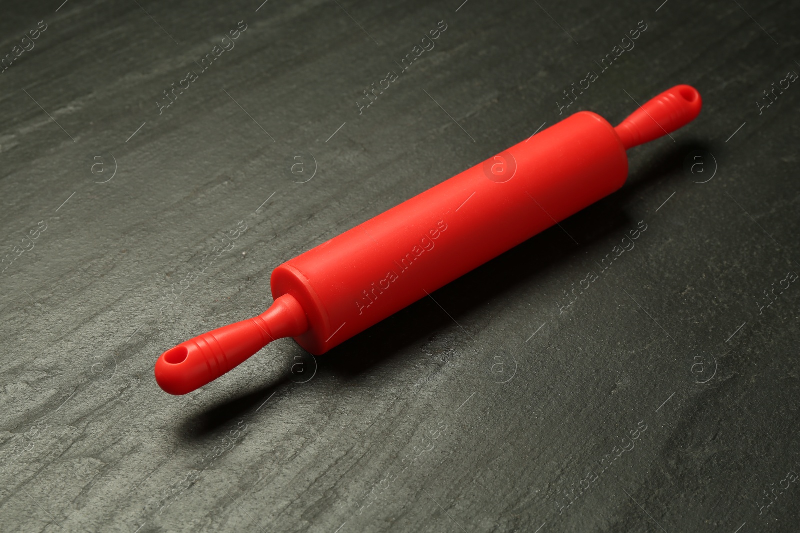 Photo of Red rolling pin on dark gray textured table