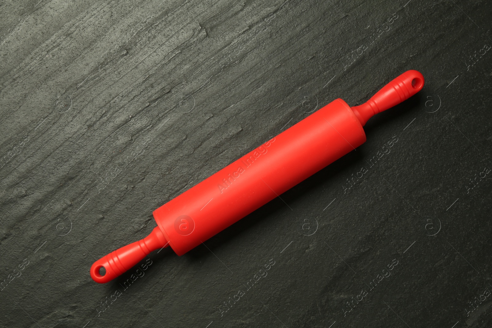 Photo of Red rolling pin on dark gray textured table, top view