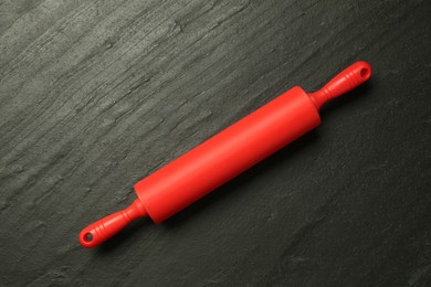 Photo of Red rolling pin on dark gray textured table, top view