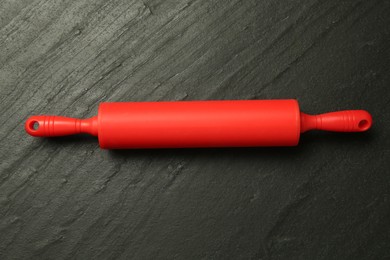 Photo of Red rolling pin on dark gray textured table, top view