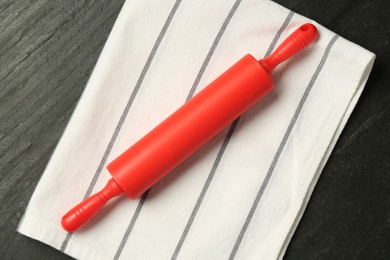 Photo of Red rolling pin and napkin on dark gray textured table, top view