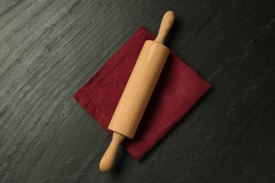 Photo of Wooden rolling pin and napkin on dark gray textured table, top view