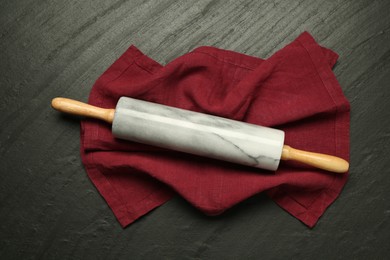 Photo of Rolling pin and napkin on dark gray textured table, top view