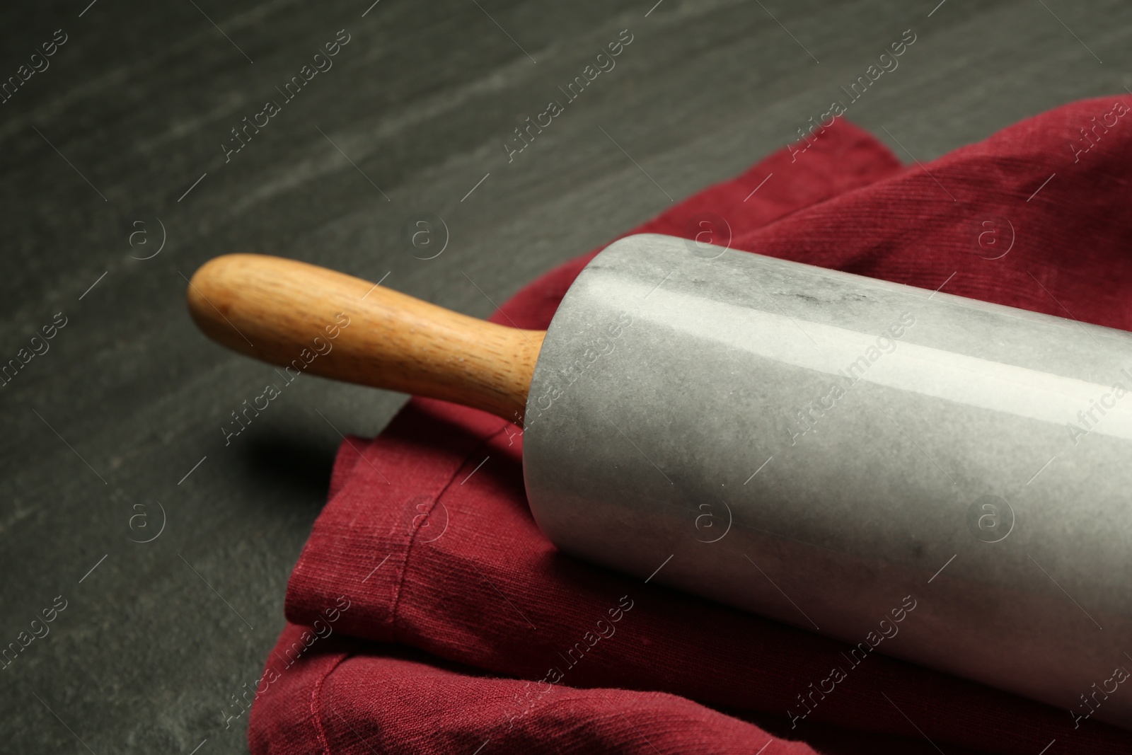 Photo of Rolling pin and napkin on dark gray table, closeup