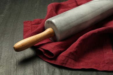 Photo of Rolling pin and napkin on dark gray textured table, closeup