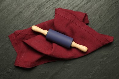 Photo of Rolling pin and napkin on dark gray textured table, top view