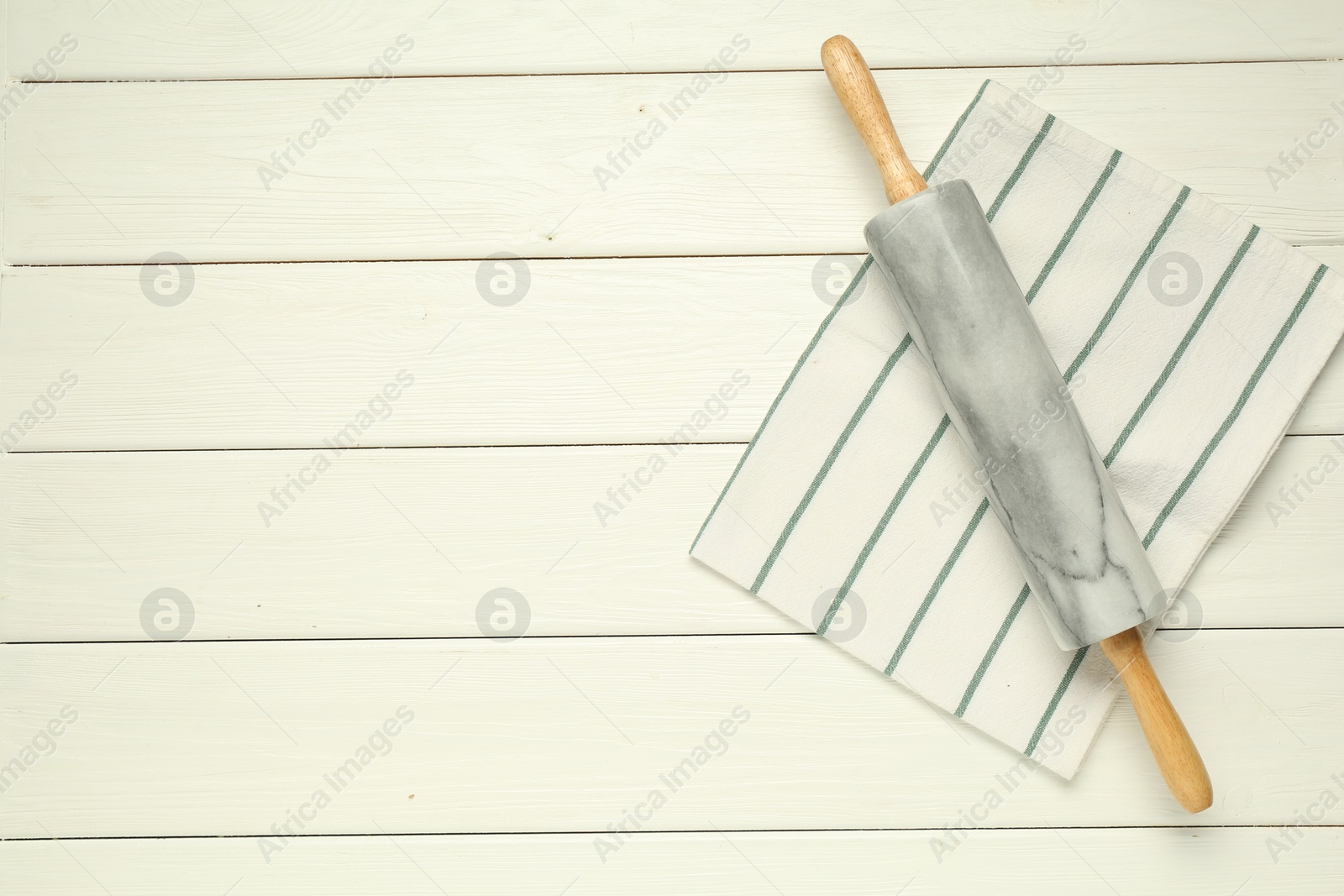 Photo of Rolling pin and napkin on white wooden table, top view. Space for text