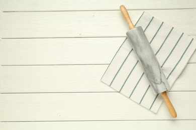 Photo of Rolling pin and napkin on white wooden table, top view. Space for text