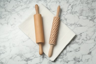 Photo of Rolling pins and napkin on light marble table, flat lay