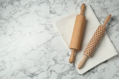 Photo of Rolling pins and napkin on light marble table, flat lay. Space for text