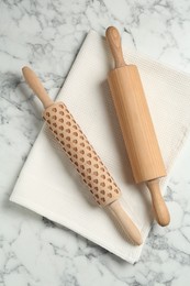 Photo of Rolling pins and napkin on light marble table, flat lay