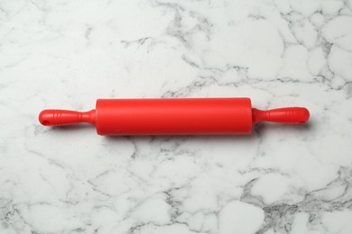 Photo of Red rolling pin on light marble table, top view