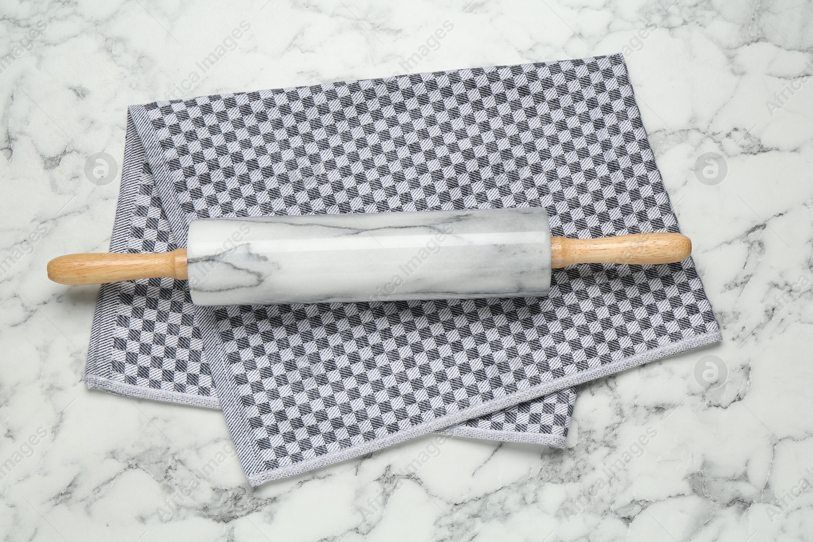 Photo of Rolling pin and napkin on light marble table, top view