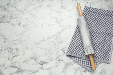 Photo of Rolling pin and napkin on light marble table, top view. Space for text