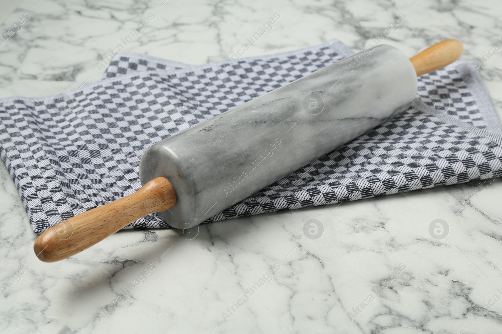 Photo of Rolling pin and napkin on light marble table, closeup