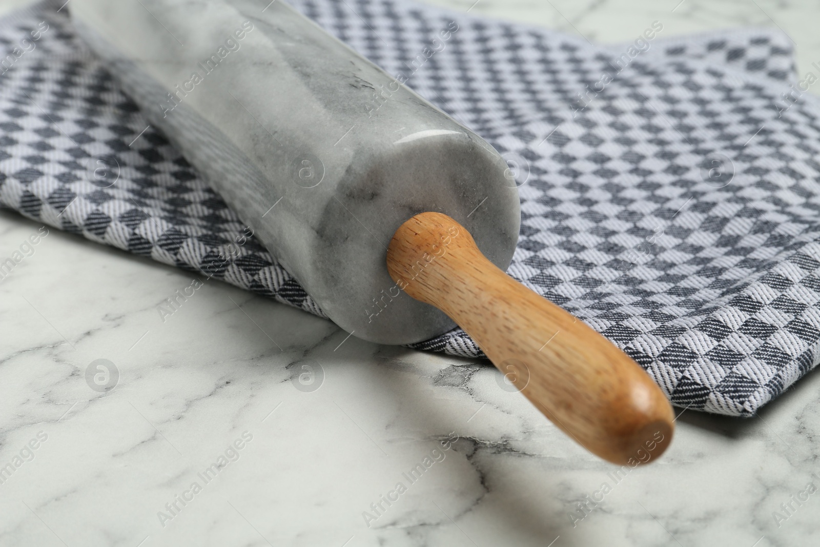 Photo of Rolling pin and napkin on light marble table, closeup