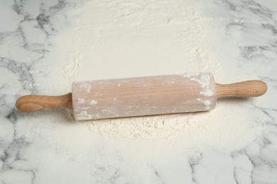 Photo of Rolling pin and flour on light marble table