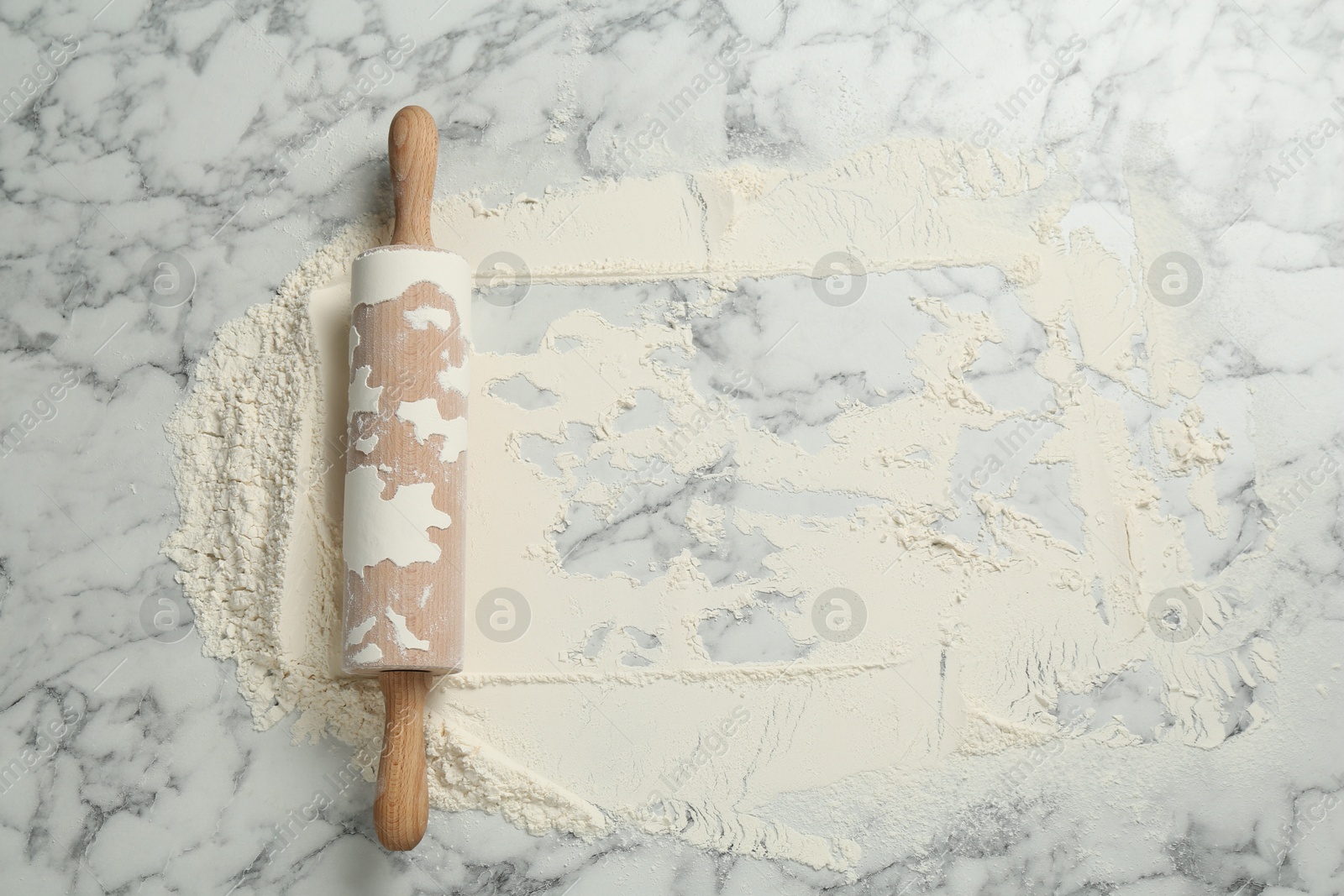 Photo of Rolling pin and flour on light marble table, top view. Space for text