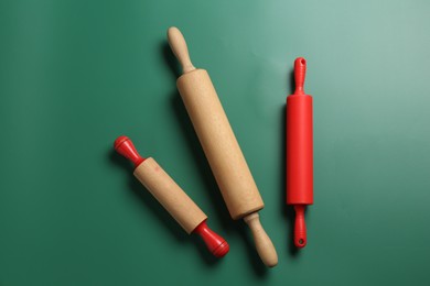 Photo of Different rolling pins on green background, flat lay