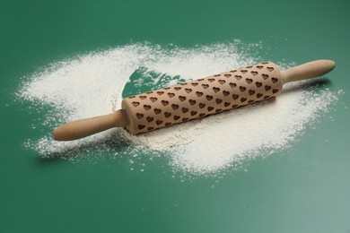 Photo of Wooden rolling pin and flour on green background