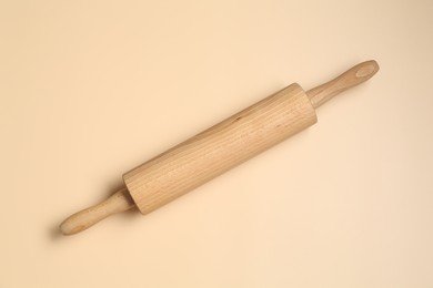 Photo of Wooden rolling pin on beige background, top view