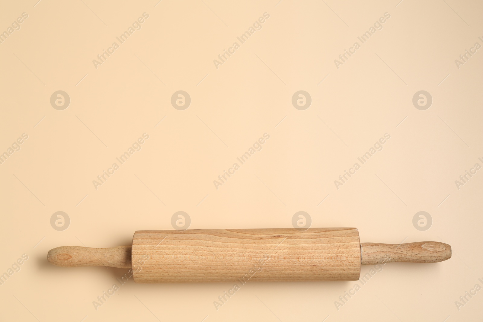 Photo of Wooden rolling pin on beige background, top view. Space for text