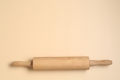 Photo of Wooden rolling pin on beige background, top view. Space for text