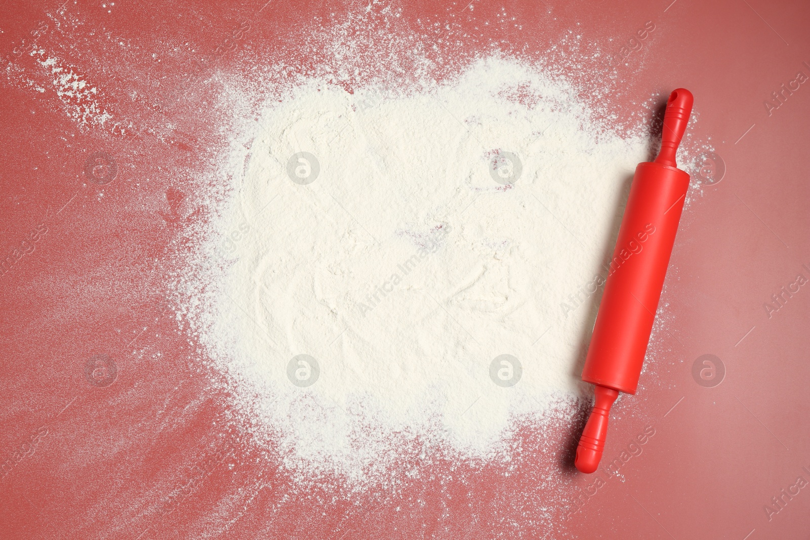 Photo of Rolling pin and flour on color background, top view. Space for text