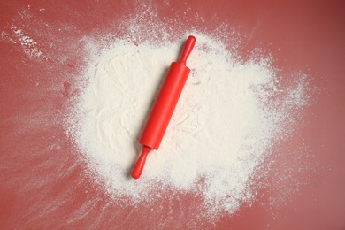 Photo of Rolling pin and flour on color background, top view