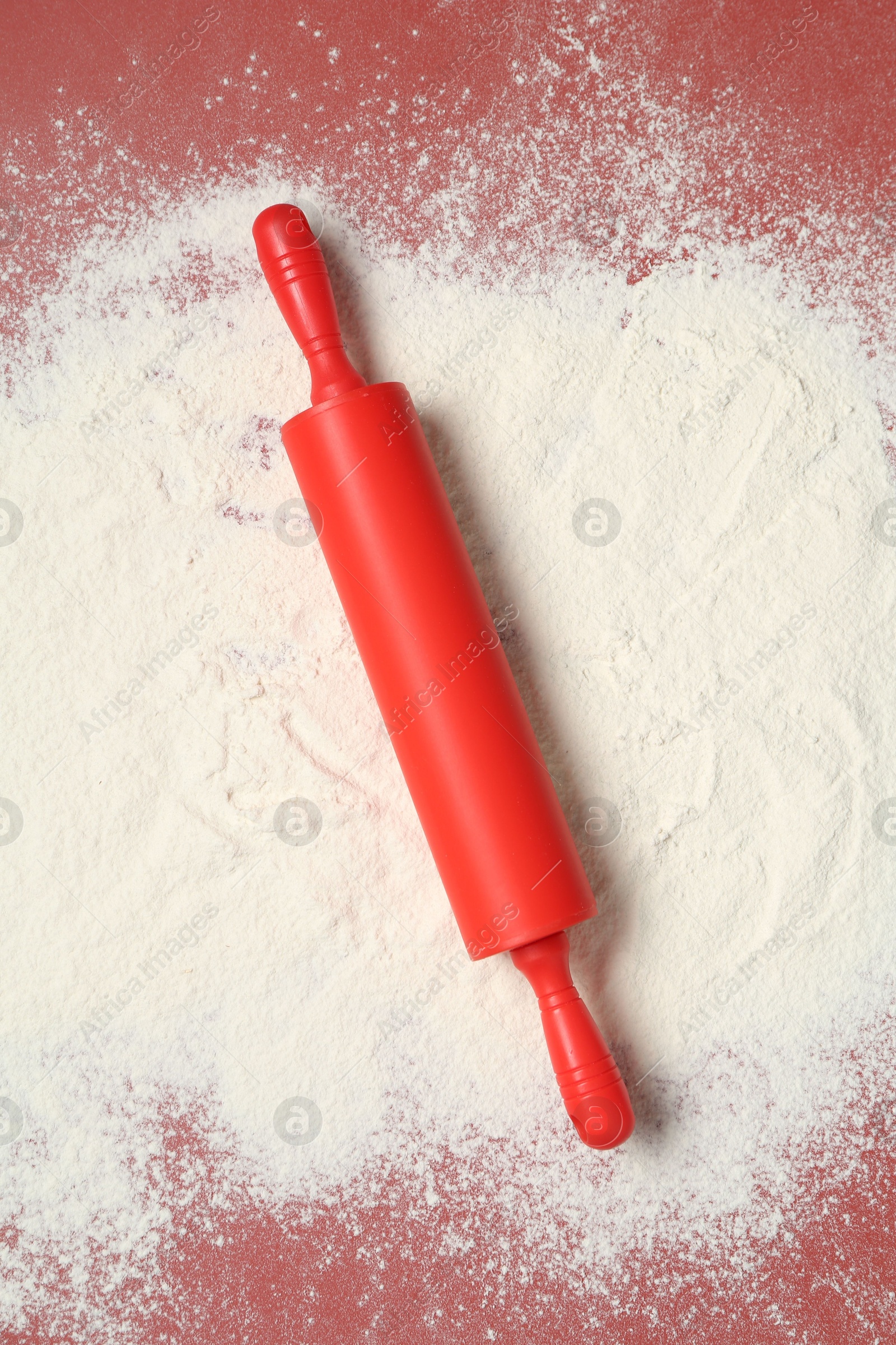 Photo of Rolling pin and flour on color background, top view