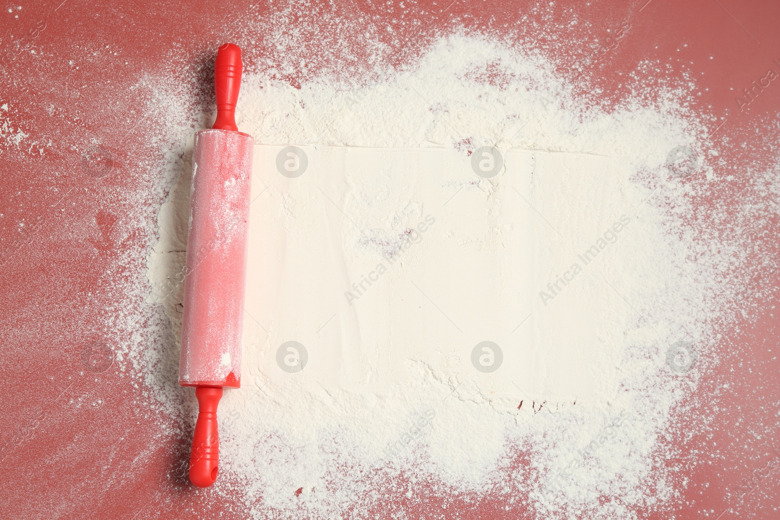 Photo of Rolling pin and flour on color background, top view. Space for text