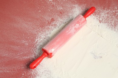 Photo of Rolling pin and flour on color background, top view