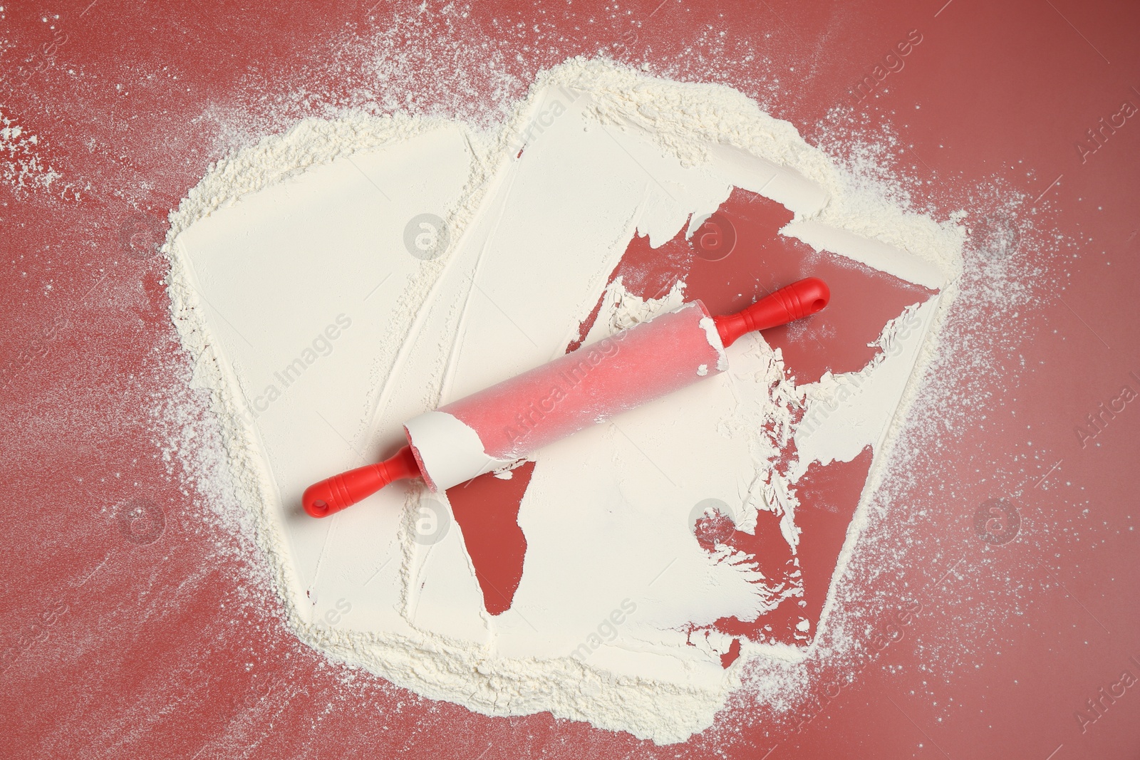 Photo of Rolling pin and flour on color background, top view