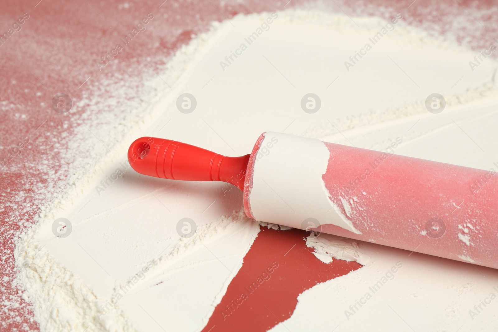 Photo of Rolling pin and flour on color background, closeup