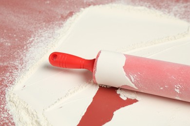 Photo of Rolling pin and flour on color background, closeup