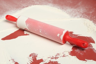 Photo of Rolling pin and flour on color background, closeup