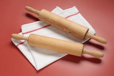 Photo of Wooden rolling pins and napkin on red background, above view