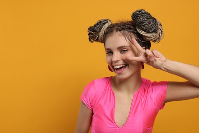 Photo of Beautiful woman with braided double buns on yellow background, space for text