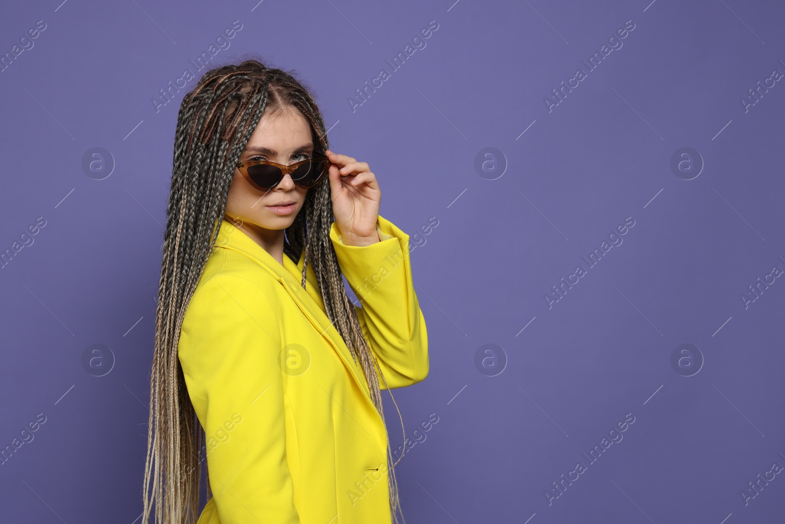 Photo of Beautiful woman with long african braids on purple background, space for text