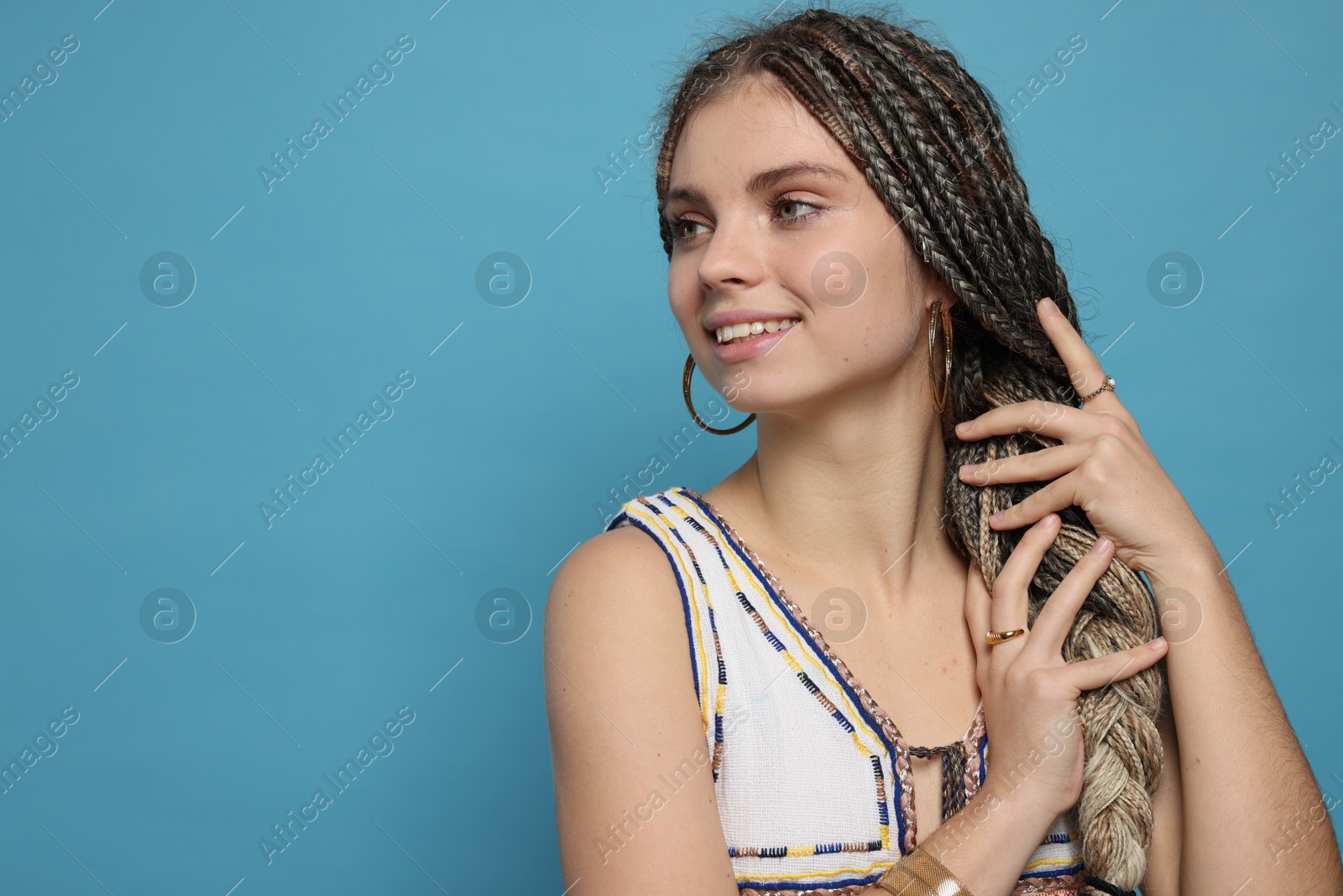 Photo of Beautiful woman with long african braids on blue background, space for text