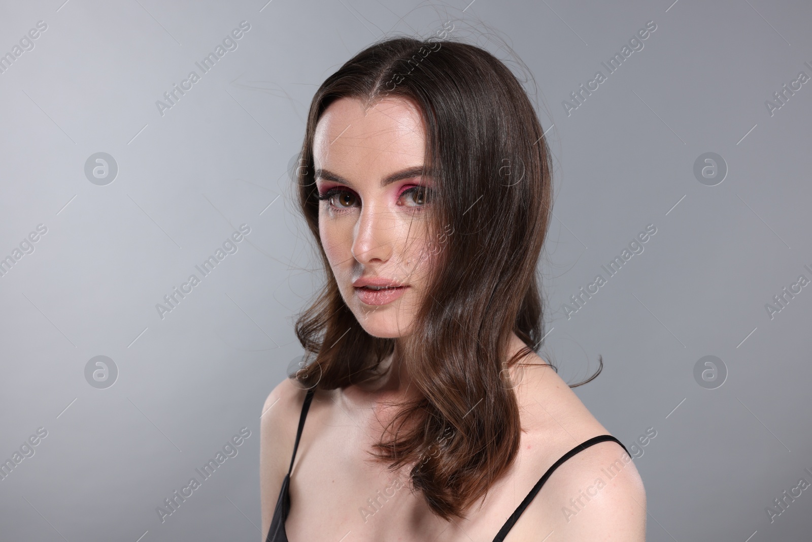 Photo of Portrait of beautiful young woman with stylish makeup and gorgeous hair on light grey background