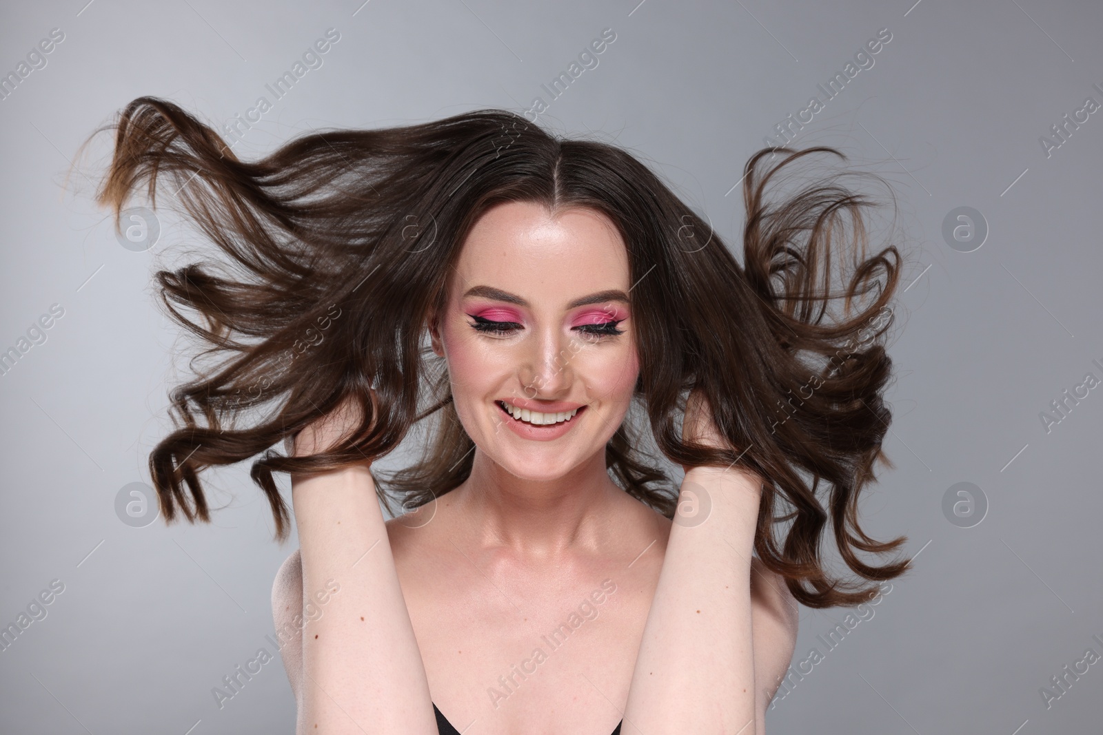 Photo of Portrait of beautiful young woman with stylish makeup and gorgeous hair on light grey background