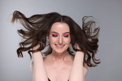 Photo of Portrait of beautiful young woman with stylish makeup and gorgeous hair on light grey background