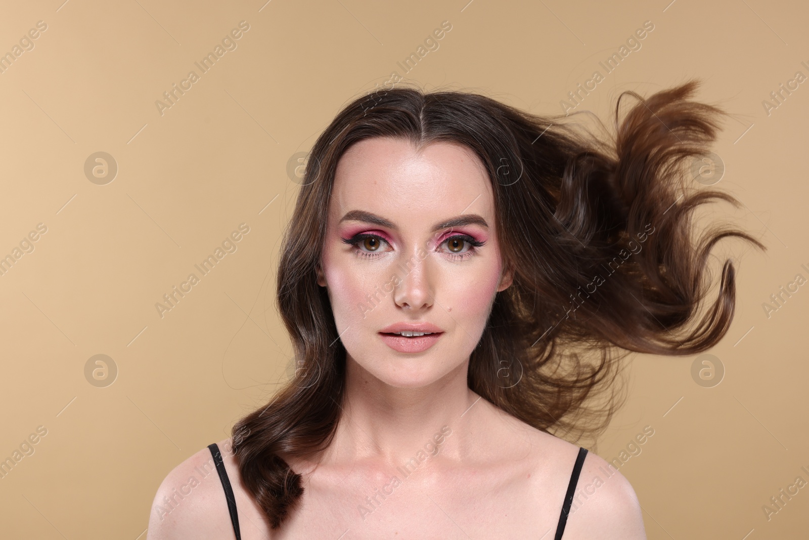 Photo of Portrait of beautiful young woman with stylish makeup and gorgeous hair on beige background