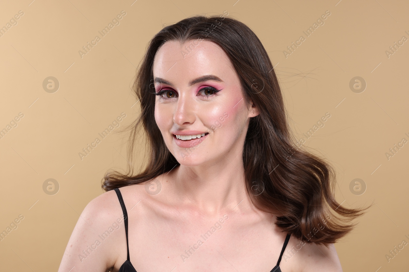 Photo of Portrait of beautiful young woman with stylish makeup and gorgeous hair on beige background