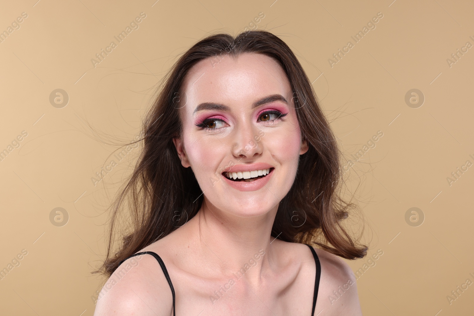 Photo of Portrait of beautiful young woman with stylish makeup and gorgeous hair on beige background