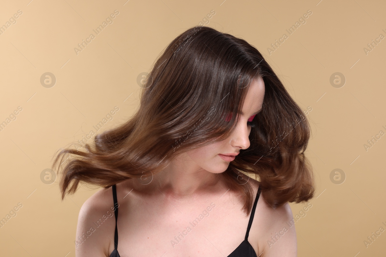 Photo of Portrait of beautiful young woman with stylish makeup and gorgeous hair on beige background